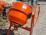 an orange cement mixer sitting in front of a building on a dirt road