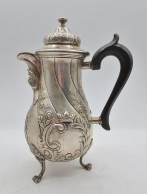 une cafetière ancienne en argent avec une poignée noire sur un support