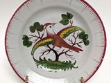 a red and white plate with a bird and a snake on it