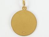 a close up of a gold disc pendant on a white background