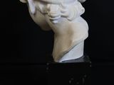 a white marble bust of a woman with a hat on top of it