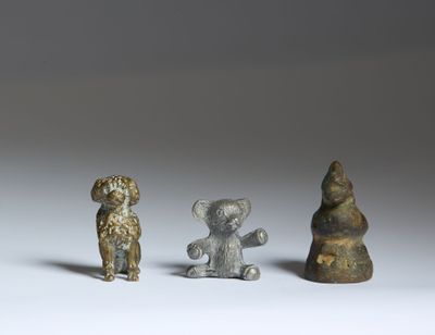 trois petites figurines d'animaux en bronze et un ours sur un fond blanc