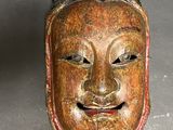 an old wooden mask with a face on a gray surface