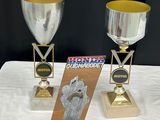 deux trophées posés sur une table avec un fond noir