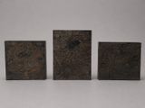 three bronze boxes with designs on them on a white surface