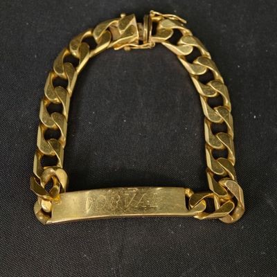 gros plan d'un bracelet en or sur une surface noire