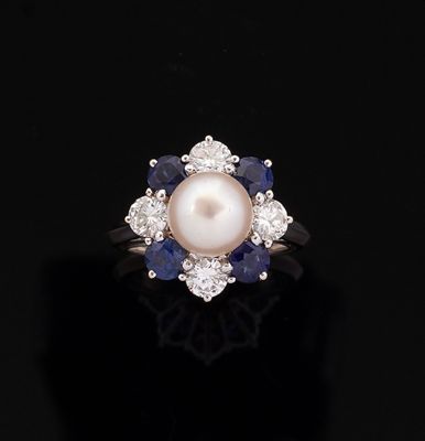 a close up of a pearl and sapphire ring on a black surface