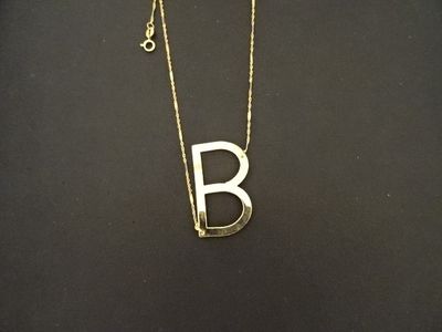 un collier en or sur lequel figure la lettre « b »