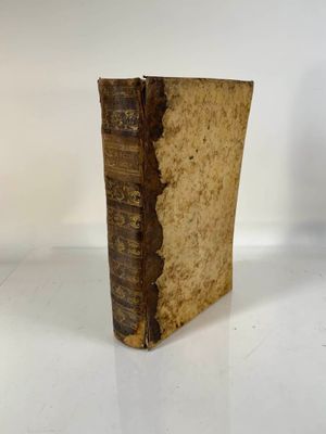 an old book sitting on top of a table next to a white wall