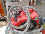 une photo d'un aspirateur rouge et gris posé sur un établi