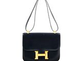 a black leather handbag with gold hardware on the handle