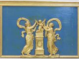 une plaque dorée sur un mur bleu, avec deux femmes