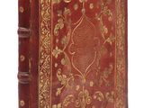 un vieux livre à la couverture rouge ornée de motifs dorés