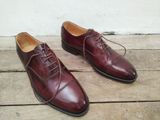 chaussures en cuir bordeaux à lacets pour homme, sur un parquet