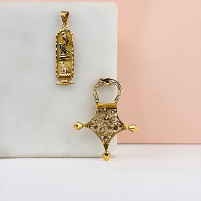 une paire de boucles d'oreilles en or et un pendentif posés sur un bloc de marbre