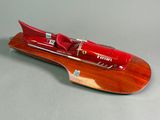 une maquette rouge d'un hors-bord posée sur une surface grise