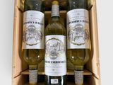 des bouteilles de vin sont disposées dans une caisse en bois posée sur une surface blanche