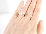 a woman ' s hand with a pearl ring on it
