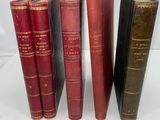five old books lined up in a row on a white surface