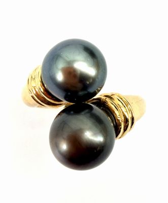 pair of black pearls on a gold plated ring on a white background