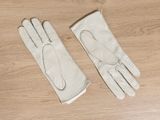 pair of white leather gloves on a wooden table with a pair of scissors