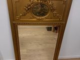 un miroir avec un cadre doré et une horloge dessus
