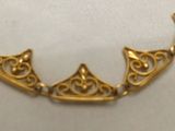 an image of a gold necklace on a white surface