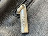 a close up of the zipper of a black leather purse