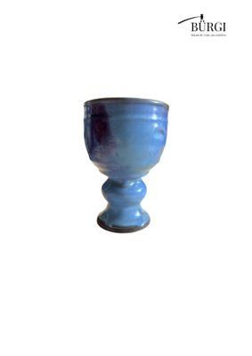a blue glass cup sitting on a white surface