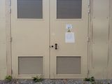 deux portes situées sur le côté d'un immeuble sur lequel est accrochée une enseigne