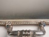an antique silver plate with a handle on a white surface