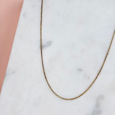 a gold chain necklace on a marble surface