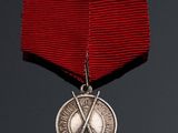 a close up of a medal with two crossed swords on a red ribbon