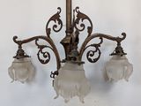 a chandelier with three glass shades hanging from the ceiling