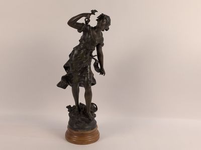 une statue antique en bronze représentant une femme tenant une fleur