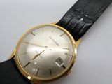une montre en or avec un bracelet noir sur un fond blanc