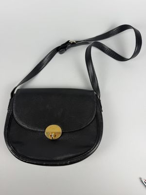 a black purse with a gold button on it sitting on a white surface