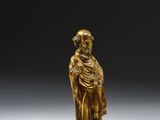 a gold figurine of a man with a hat and robe