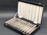 un coffret noir contenant de l'argenterie, posé sur une surface grise
