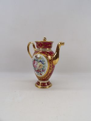un petit vase rouge et doré orné de fleurs