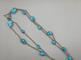 un gros plan d'un collier composé de perles de turquoise sur un fond blanc