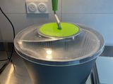 a large metal bowl with a green lid on a kitchen counter