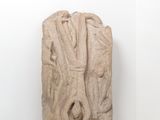 sculpture représentant un visage sur un bloc de pierre dans une pièce blanche