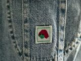 someone is wearing a jean jacket with a rose patch on it
