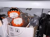 an orange pumpkin sitting inside of a refrigerator next to a black bottle