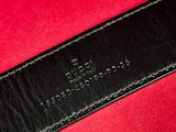 a close up of a black leather belt on a red surface