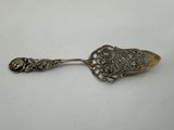 a silver spoon with ornate design on it sitting on a white surface