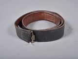 an old belt with a metal buckle on a white surface