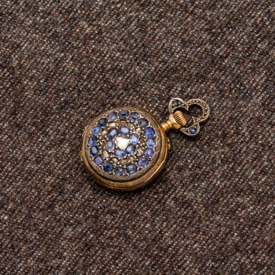 une petite montre de poche en or ornée de pierres bleues