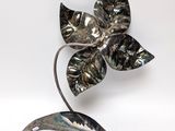sculpture of a metal flower on a metal stand against a white background